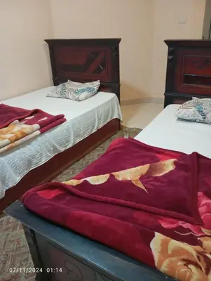 two beds in a room with red blankets at شقة في موا بلازا كورنيش النيل اسوان Apartment in Mowa Plaza Aswan Nile Corniche in Aswān