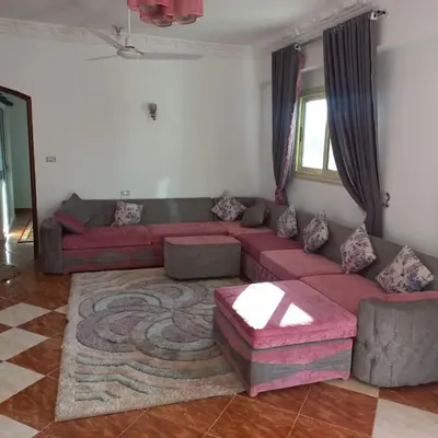 a living room with a red couch and a rug at Banana Guest House in Luxor