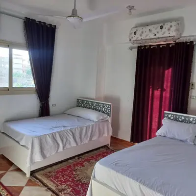 two beds in a room with red curtains at Banana Guest House in Luxor