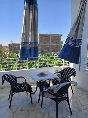 a patio with four chairs and a table on a balcony at Nile Rose Hause in Al Karnak