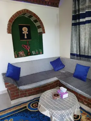 a room with a couch with blue pillows and a table at Nile Rose Hause in Al Karnak