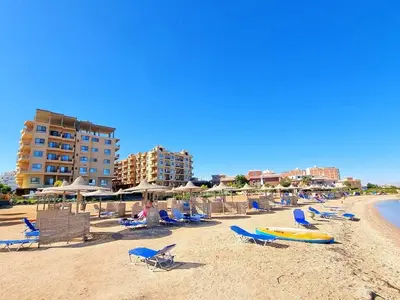 a beach with chairs and umbrellas and a building at Turtles beach resort ED Seaview Apartment in Hurghada
