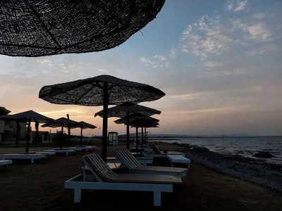 a group of chairs and umbrellas on a beach at Fanadir Bay Resort, rental chalet apartment in Hurghadana in Hurghada