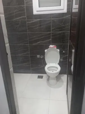 a bathroom with a toilet in a black tiled wall at فندق تيم وتميم in Luxor
