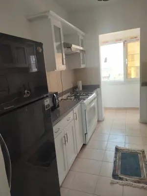 a kitchen with black appliances and a tile floor at comfort marina 5 apartment,s in Hurghada