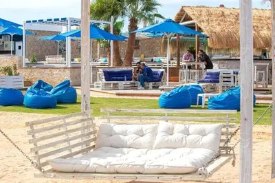 a white couch sitting on a beach with blue umbrellas at comfort marina 5 apartment,s in Hurghada