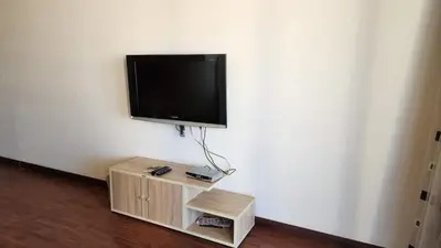a flat screen tv hanging on a wall with a wooden stand at Apartment in the view 207 hill view in Hurghada