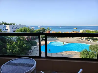 a balcony with a view of a swimming pool and the ocean at Studio for rent 206 in Hurghada