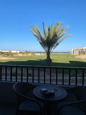 a table and chairs on a balcony with a palm tree at Soma Breeze Sea and Golf view in Hurghada