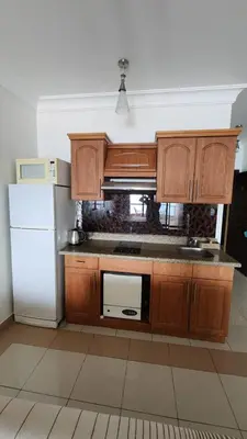 a kitchen with wooden cabinets and a white refrigerator at Studio for rent in the view 114 in Hurghada