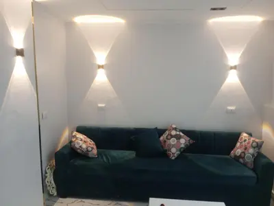 a living room with a green couch and three lights at white popular apartment in Al Karnak