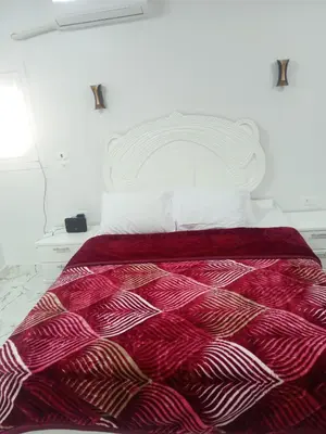 a bedroom with a bed with a red and white comforter at white popular apartment in Al Karnak