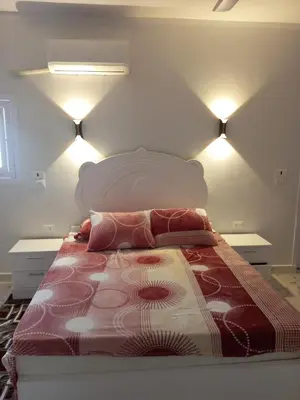 a bedroom with a large bed with two lights at white popular apartment in Al Karnak
