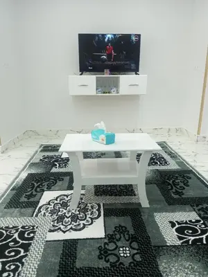 a white coffee table in a living room with a tv at white popular apartment in Al Karnak