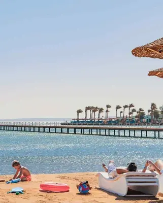 a group of people sitting on the beach near the water at Scandic Resort Hurghada in Hurghada