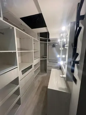 a walk in closet with white cabinets and a bench at Sky star 130 in Hurghada