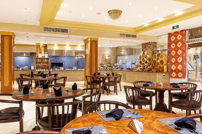 a restaurant with wooden tables and chairs and a counter at Sunrise Solara Aqua park Resort in Banī Ghālib