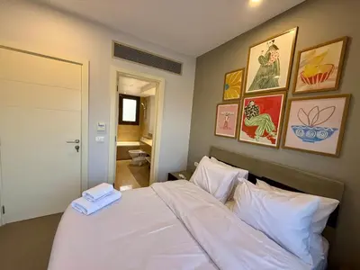 a bedroom with a white bed with paintings on the wall at Picturesque 3BR Villa- Free Lagoon Access ElGouna in Hurghada