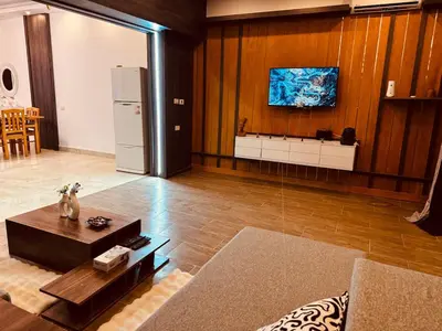 a living room with a table and a refrigerator at Prestige Home apartment in Hurghada