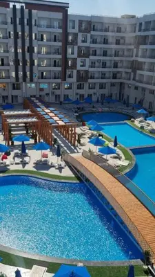 a resort with two pools with blue umbrellas at Tiba golden resort in Hurghada
