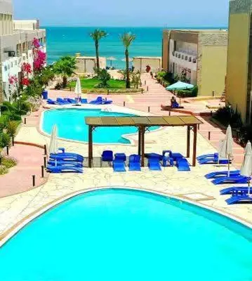 a large swimming pool with blue chairs and umbrellas at Cecilia Village in Hurghada
