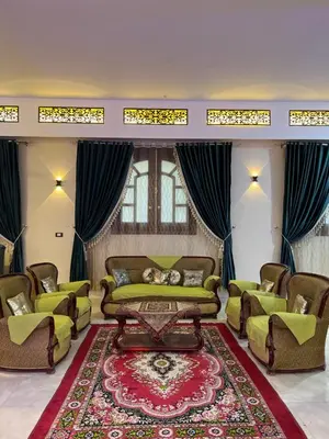 a living room with a couch and chairs and a rug at Family House in Luxor