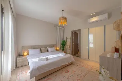 a white bedroom with a large bed and a chandelier at Stylish 3 BR Retreat at Ancient Hills El Gouna in El Gouna