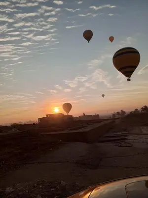 a group of hot air balloons flying in the sky at White Rose House in Luxor