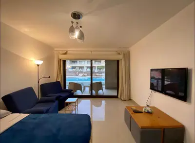 a room with a bed and a living room with a tv at G Cribs Pool Front Studio in Hurghada