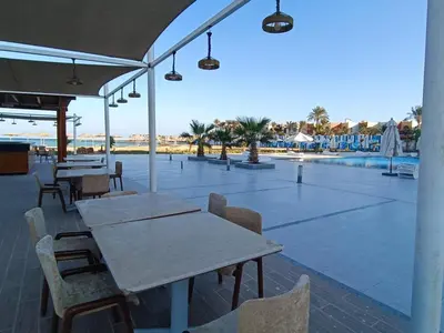 a patio with tables and chairs next to a pool at Sunset View at scandic Beach WIFI in Hurghada