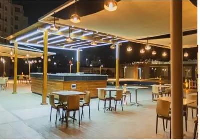 a patio with tables and chairs and a bar at Sunset View at scandic Beach WIFI in Hurghada