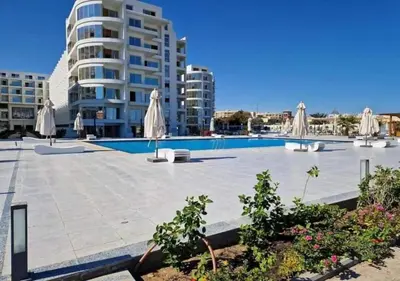 a swimming pool with umbrellas and a building at Sunset View at scandic Beach WIFI in Hurghada