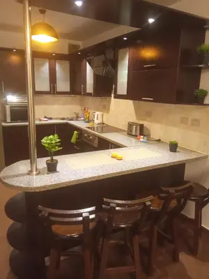a kitchen with a counter with four chairs around it at , كمبواند قمريه in Hurghada