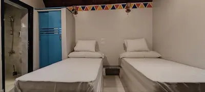 two beds in a small room with a blue door at Kemet Guest House in Aswan