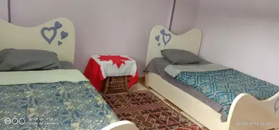 a room with two beds and a table in it at Al Agamay Nile view guest House in Jazīrat Aswān