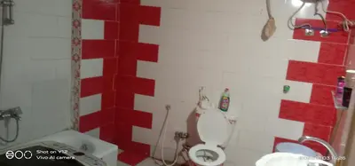 a red and white bathroom with a toilet and a sink at Al Agamay Nile view guest House in Jazīrat Aswān
