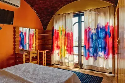 a bedroom with a bed and a window with colorful curtains at Moon of Nuba House in Aswan