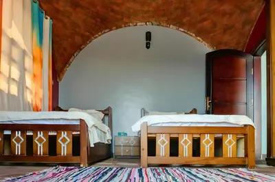 two beds in a room with an archway at Moon of Nuba House in Aswan