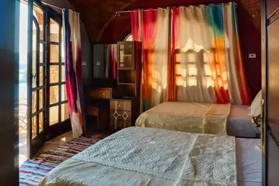 a bedroom with two beds and a colorful curtain at Moon of Nuba House in Aswan