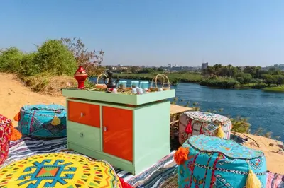 a kitchen with a counter and chairs next to a river at Moon of Nuba House in Aswan