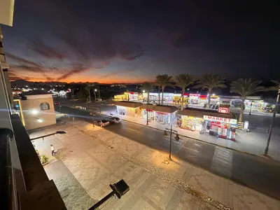 a night view of a street with shops and palm trees at Relaxing apartment in Hurghada