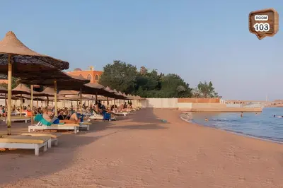 a beach with people sitting on chairs and umbrellas at Relaxing apartment in Hurghada