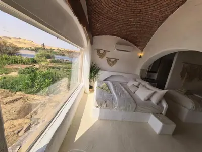 a bedroom with a bed and a large window at Nala Narty Nubian House & Organic Farm in Aswan