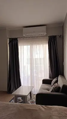 a living room with a couch and a table in front of a window at Cozy studio Florenza Khamsin in Hurghada