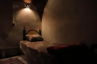 a dark room with a bed and a light at Carmah Nubian Guesthouse in Aswan