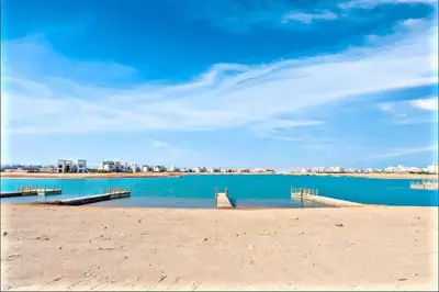 a beach with two docks in the water at inchant sands elgouna luxury villa in Hurghada