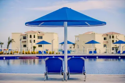 two blue chairs under an umbrella next to a pool at Albatros Makadi Resort - 24 HRS All Inclusive in Hurghada