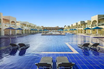 a swimming pool with chairs and umbrellas in a resort at Albatros Makadi Resort - 24 HRS All Inclusive in Hurghada
