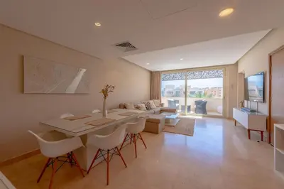 a living room with a table and a couch at Coastal Vibe 2BR Mangroovy Gouna with Rooftop Cinema, BBQ, Pool & Beach Access in Hurghada