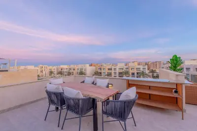a table and chairs on a balcony with a view at Coastal Vibe 2BR Mangroovy Gouna with Rooftop Cinema, BBQ, Pool & Beach Access in Hurghada